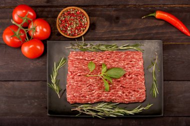 kağıt üzerinde çiğ kıyma, siyah arka plan üzerinde domates, biber, soğan, baharat ve baharat ile burger için malzemeler. Üst görünüm ve kopyalama alanı