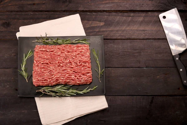 raw minced meat on paper, ingredients for burger with tomato, pepper, onion, spices and seasonings on black background. Top view and copy space