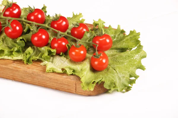Almuerzo orgánico jugoso fresco maduro de tomates cherry en la tabla de cortar con lechuga verde en una mesa blanca — Foto de Stock