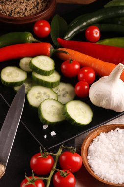 Sağlıklı yiyecekler. Siyah tabak ve taş kesme tahtası ve ahşap arka plan üzerinde Sebzeler.