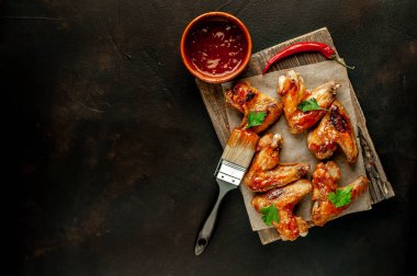 Beton bir tabloda bir kesme tahtası üzerinde maydanoz ile Barbekü soslu tavuk kanadı ızgara. Kopya alanı ile Üstten Görünüm.