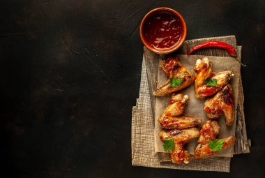 Beton bir tabloda bir kesme tahtası üzerinde maydanoz ile Barbekü soslu tavuk kanadı ızgara. Kopya alanı ile Üstten Görünüm.