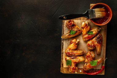 Beton bir tabloda bir kesme tahtası üzerinde maydanoz ile Barbekü soslu tavuk kanadı ızgara. Kopya alanı ile Üstten Görünüm.