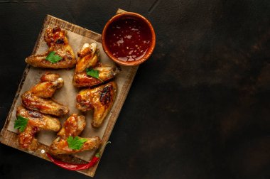 Beton bir tabloda bir kesme tahtası üzerinde maydanoz ile Barbekü soslu tavuk kanadı ızgara. Kopya alanı ile Üstten Görünüm.
