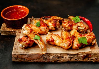 Beton bir tabloda bir kesme tahtası üzerinde maydanoz ile Barbekü soslu tavuk kanadı ızgara. Kopya alanı ile Üstten Görünüm.