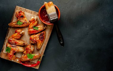 Beton bir tabloda bir kesme tahtası üzerinde maydanoz ile Barbekü soslu tavuk kanadı ızgara. Kopya alanı ile Üstten Görünüm.