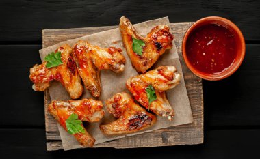 Beton bir tabloda bir kesme tahtası üzerinde maydanoz ile Barbekü soslu tavuk kanadı ızgara.