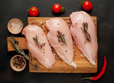 Çiğ tavuk göğsü fileto, ahşap kesme tahtası baharatlar ile pişirme için hazır. belirli bir arka plan üzerinde. 