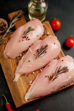 Çiğ tavuk göğsü fileto, ahşap kesme tahtası baharatlar ile pişirme için hazır. belirli bir arka plan üzerinde. 