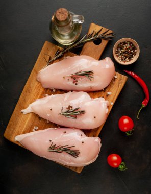 Çiğ tavuk göğsü fileto, ahşap kesme tahtası baharatlar ile pişirme için hazır. belirli bir arka plan üzerinde. 