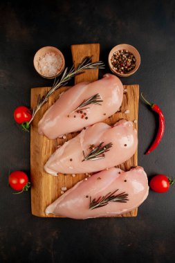 Çiğ tavuk göğsü fileto, ahşap kesme tahtası baharatlar ile pişirme için hazır. belirli bir arka plan üzerinde. 