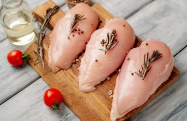 Çiğ tavuk göğsü fileto ahşap kesme tahtası baharatlar ile pişirme için hazır. ahşap bir masaya.