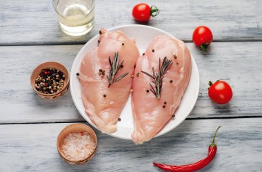 Çiğ tavuk göğsü fileto ahşap kesme tahtası baharatlar ile pişirme için hazır. ahşap bir masaya
