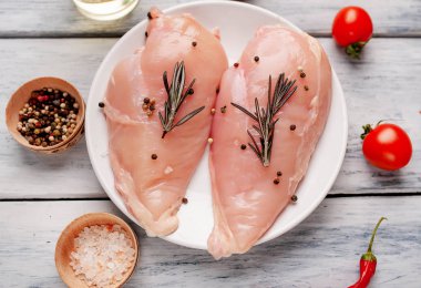 Çiğ tavuk göğsü fileto ahşap kesme tahtası baharatlar ile pişirme için hazır. ahşap bir masaya