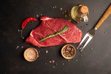 Malzemelerle büyük ham New York bifteği. karanlık taş arka plan üzerinde.