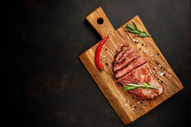 Bir kesme tahtası üzerinde malzemelerle New York siyah angus biftek yemek hazır. Karanlık bir taş zemin üzerine akşam yemeğine hazır yemek. kopya alanı ile