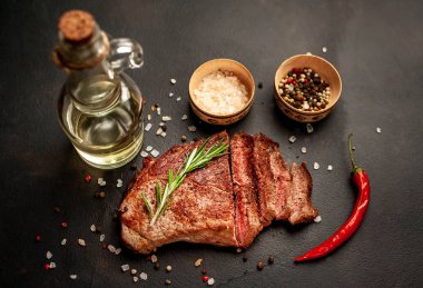 New York siyah angus sığır eti doğurmak bir beton zemin üzerine malzemelerle biftek yemek hazır. Karanlık bir taş zemin üzerine akşam yemeğine hazır yemek