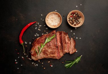 New York siyah angus sığır eti doğurmak bir beton zemin üzerine malzemelerle biftek yemek hazır. Karanlık bir taş zemin üzerine akşam yemeğine hazır yemek