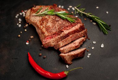 New York siyah angus sığır eti doğurmak bir beton zemin üzerine malzemelerle biftek yemek hazır. Karanlık bir taş zemin üzerine akşam yemeğine hazır yemek