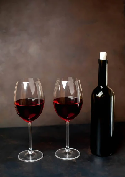 Red wine glasses and a bottle with wine on a stone background. View from above