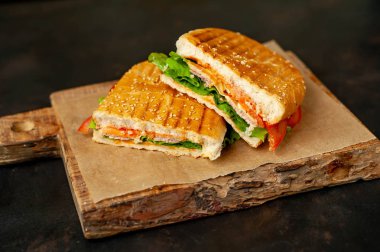 Taş arka planda ahşap doğrama tahtasında ızgara Panini sandviç