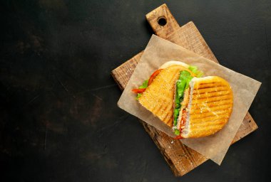 Taş arka planda ahşap doğrama tahtasında ızgara Panini sandviç