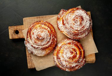 Taze ev yapımı Cinnabon ahşap doğrama tahtasında kurutulmuş Hindistan cevizi ile serpilir
