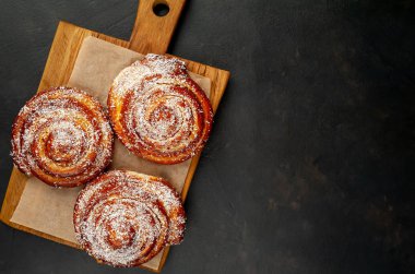 Taze ev yapımı Cinnabon ahşap doğrama tahtasında kurutulmuş Hindistan cevizi ile serpilir