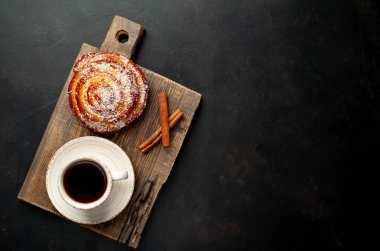 Taş arka planda ahşap doğrama tahtasında kahve ve tarçın kabuğu ile taze Cinnabon