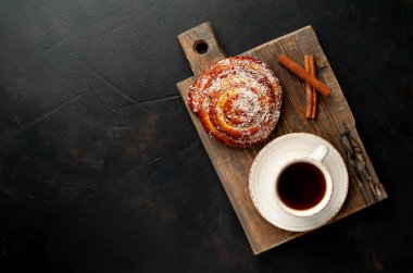 Taş arka planda ahşap doğrama tahtasında kahve ve tarçın kabuğu ile taze Cinnabon