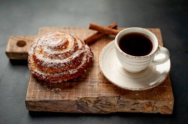 Taş arka planda ahşap doğrama tahtasında kahve ve tarçın kabuğu ile taze Cinnabon