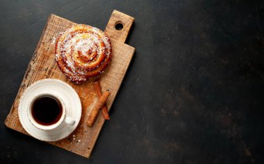 Taş arka planda ahşap doğrama tahtasında kahve ve tarçın kabuğu ile taze Cinnabon