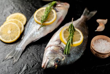 Taş arka planda limon ve biberiye dallar ile çiğ balık yakın görünümü 