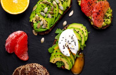 Avokado dilimleri, greyfurt, taş arka planda haşlanmış yumurta ile taze tost