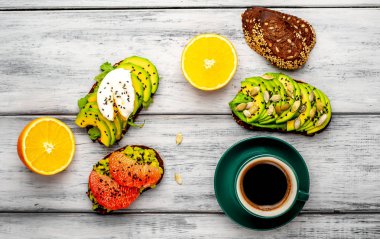 ahşap arka planda dilimlenmiş avokado, yumurta ve greyfurt ile tost ile servis edilen kahve fincan