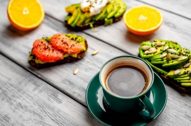 ahşap arka planda dilimlenmiş avokado, yumurta ve greyfurt ile tost ile servis edilen kahve fincan