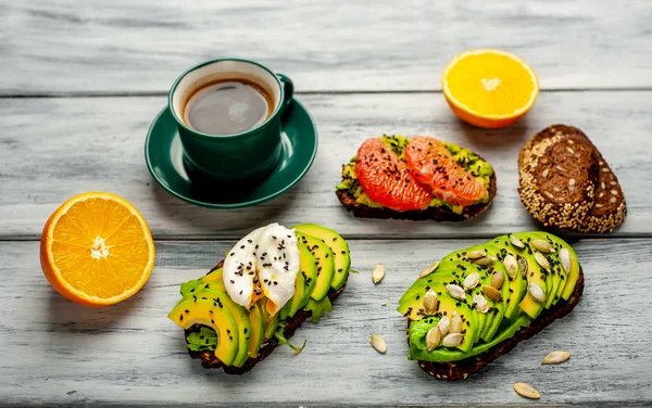 ahşap arka planda dilimlenmiş avokado, yumurta ve greyfurt ile tost ile servis edilen kahve fincan