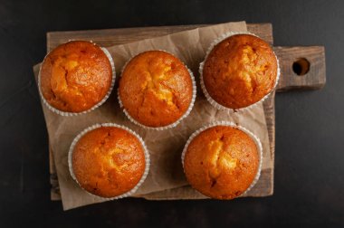 Siyah taş arka planda Ahşap Doğrama Kurulu üzerinde taze ev yapımı kekler