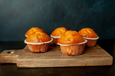 Siyah taş arka planda Ahşap Doğrama Kurulu üzerinde taze ev yapımı kekler
