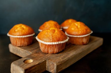 Siyah taş arka planda Ahşap Doğrama Kurulu üzerinde taze ev yapımı kekler