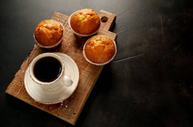 Taze pişmiş kekler ahşap tahta üzerinde bir fincan kahve ile servis