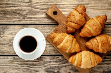 eski ahşap arka plan üzerinde ahşap tahta üzerinde taze Fransız kruvasanlar ile kahve fincan