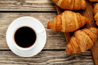 eski ahşap arka plan üzerinde ahşap tahta üzerinde taze Fransız kruvasanlar ile kahve fincan