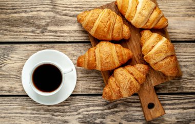 eski ahşap arka plan üzerinde ahşap tahta üzerinde taze Fransız kruvasanlar ile kahve fincan