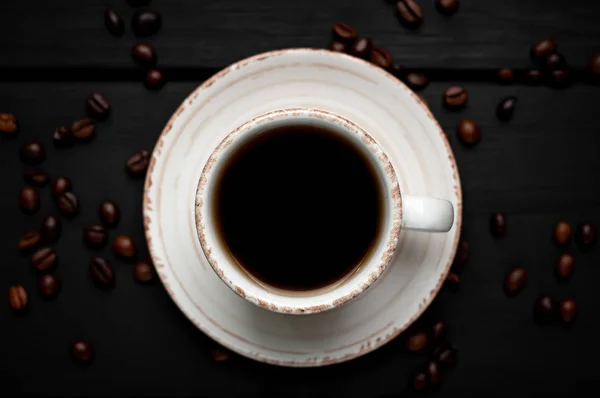 Fresh cup of coffee on black stone background with coffee beans