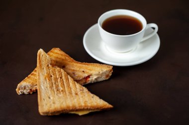 Siyah taş arka planda bir fincan kahve ile servis edilen ızgara sandviçler