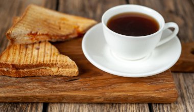 Ahşap arka planda bir fincan kahve ile servis edilen ızgara sandviçler