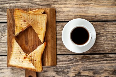 Ahşap arka planda bir fincan kahve ile servis edilen ızgara sandviçler