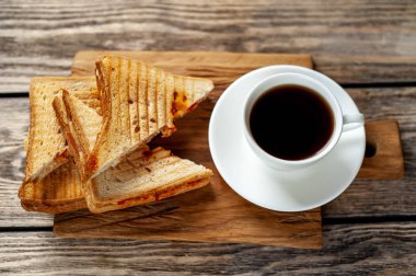 Ahşap arka planda bir fincan kahve ile servis edilen ızgara sandviçler