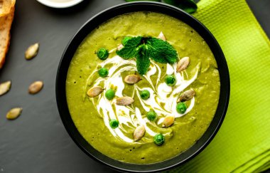 Ispanak ve brokoli yeşil krem çorbası ahşap arka planda Kabak tohumları ve Yunan yoğurt ile servis